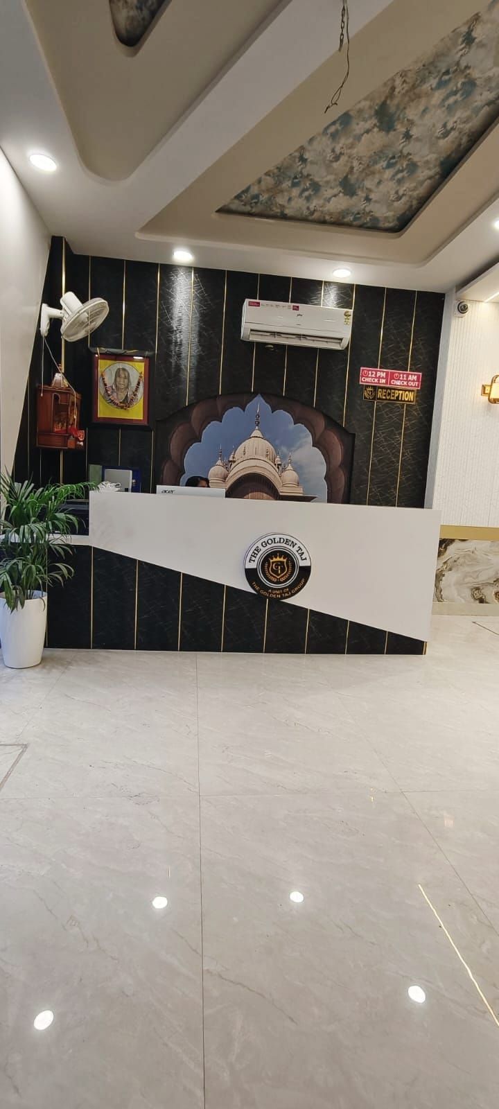 A reception desk with a logo, a clock, and a sign indicating check-in times.