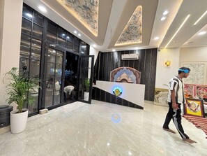 A hotel lobby with a reception desk, a large potted plant, and a marble floor. - The Golden Taj Vrindavan (Vrindavan)
