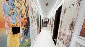 A hallway with murals on the walls, a tiled floor, and doors leading to rooms. - The Golden Taj Vrindavan (Vrindavan)