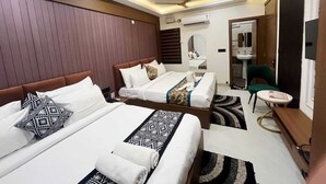 A hotel room with two beds, a sitting area, a mirror, a ceiling fan, and a bathroom visible through an open door. - The Golden Taj Vrindavan (Vrindavan)