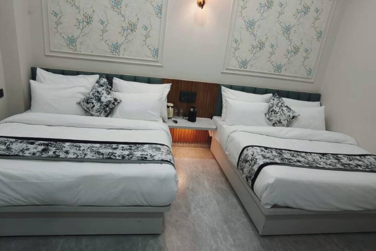 A double bed room with two beds, a nightstand, and a wall-mounted light fixture.