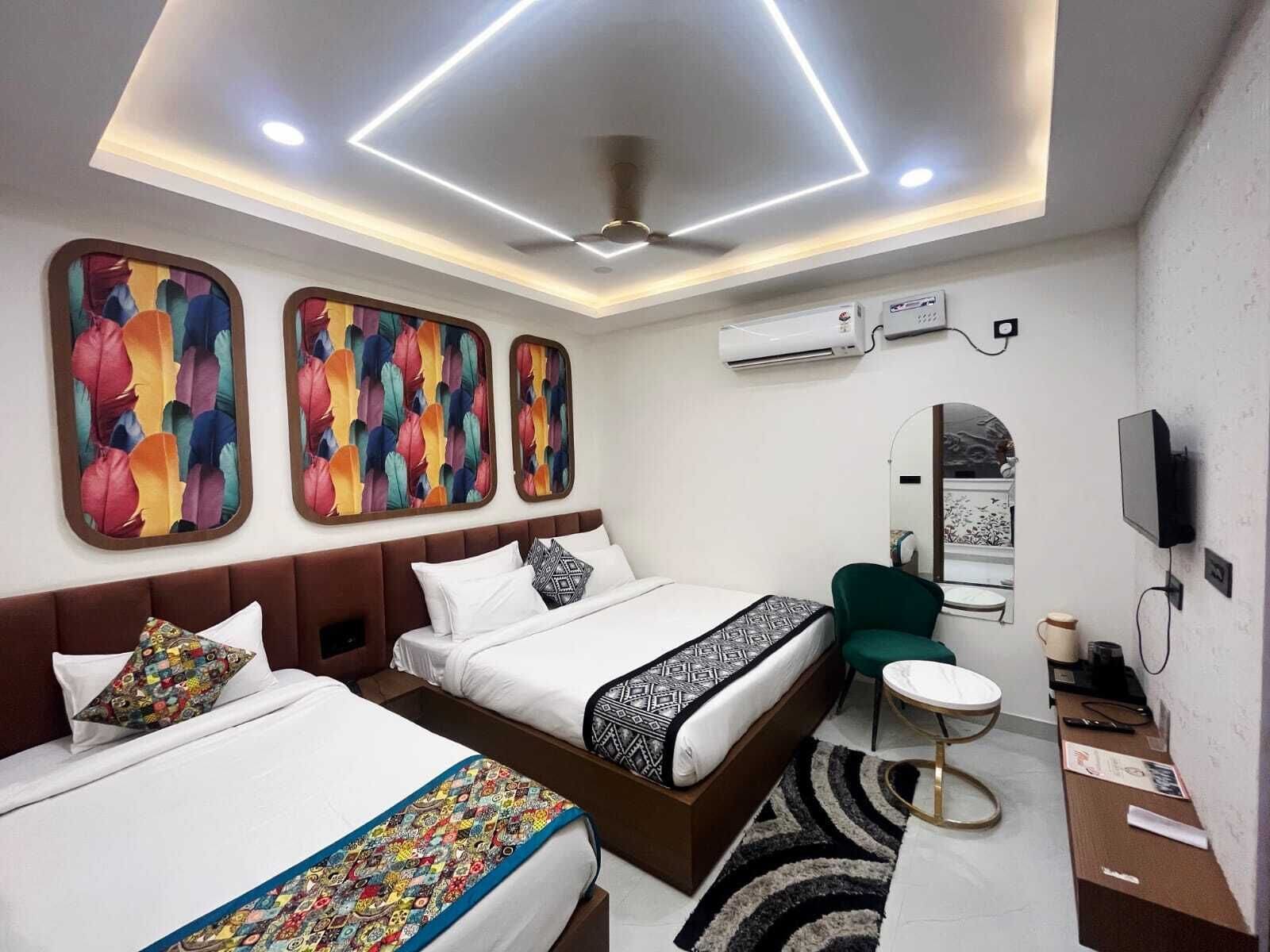 A hotel room with two beds, a desk, a chair, a TV, and an air conditioning unit.