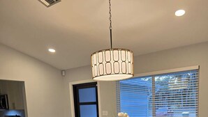 A dining area with a wooden table, six chairs, and a hanging light fixture. - Pleasant 3-bedroom house with pool in peaceful setting (Naples)