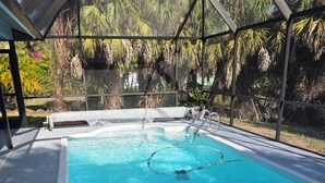 A swimming pool with clear blue water, surrounded by a covered area with a metal frame and glass panels. - Pleasant 3-bedroom house with pool in peaceful setting (Naples)