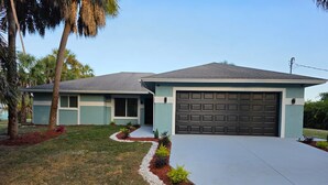 A two-story house with a garage, a driveway, and a landscaped front yard. - Pleasant 3-bedroom house with pool in peaceful setting (Naples)