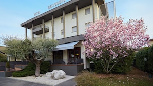 A hotel with a modern architectural design, featuring a prominent balcony and a well-maintained garden with blooming flowers. - Albergo Ristorante Belvedere (Codroipo)