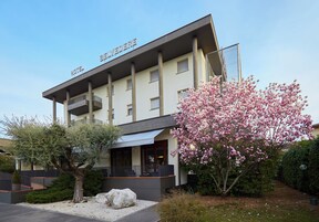 Un hotel con un diseño arquitectónico moderno, que cuenta con un balcón destacado y un jardín bien cuidado con flores en flor.