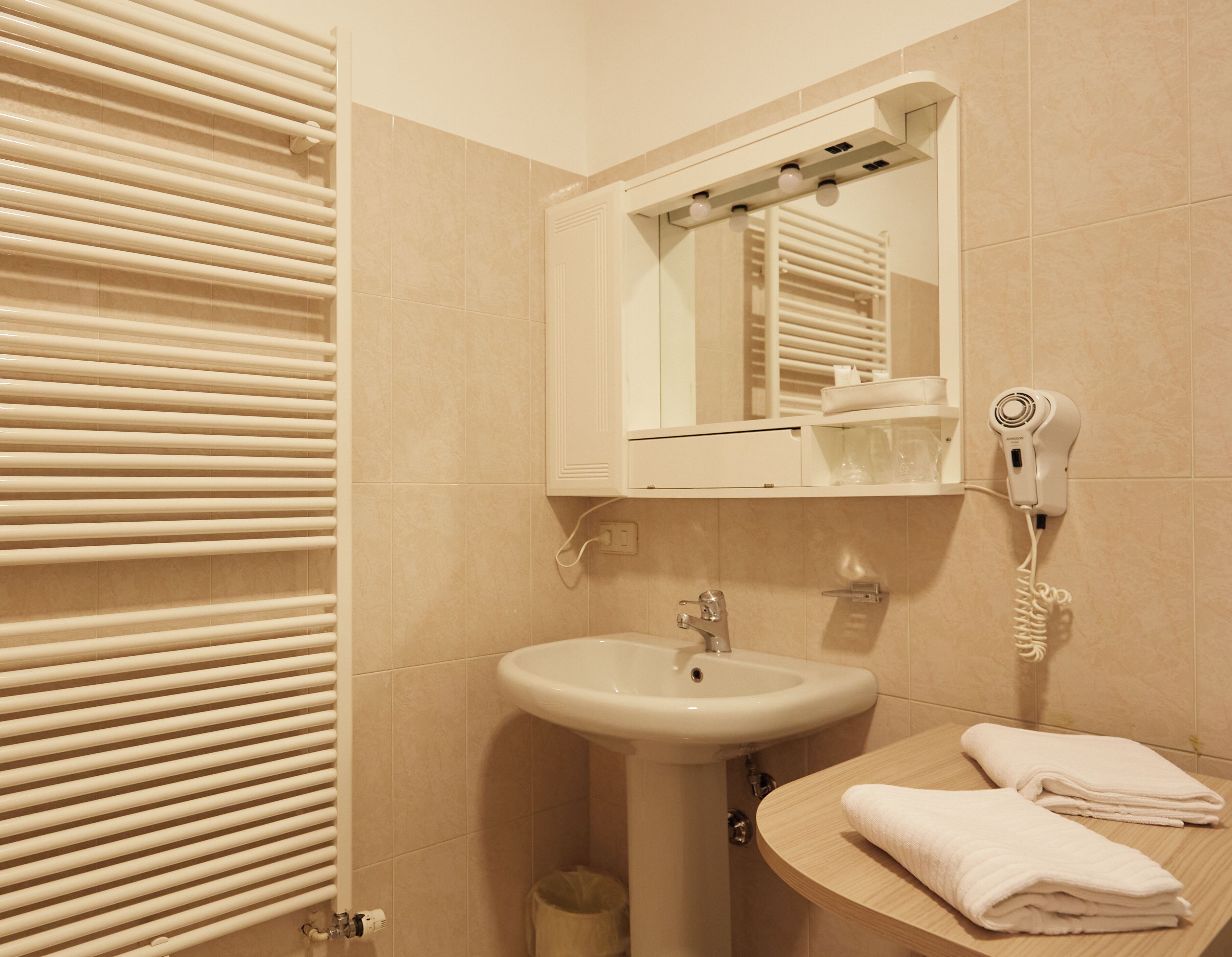 Ein Badezimmer mit Waschbecken, Spiegel, Handtuchhalter und Haartrockner.