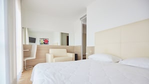 A modern hotel room with a large bed, a chair, a mirror, and a television. - Albergo Ristorante Belvedere (Codroipo)