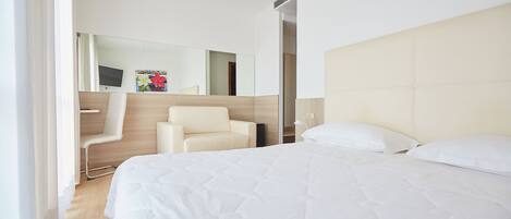 Una habitación de hotel moderna con una cama grande, una silla, un espejo y un televisor.