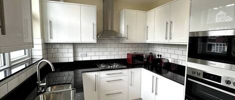 A modern kitchen with white cabinets, a black countertop, and a built-in oven.