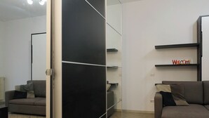 Una sala de estar moderna con un mueble corredero, un sofá gris, una mesa de centro y un estante montado en la pared con un cartel que dice 'Welcome'.