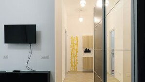 Un interior moderno con un televisor de pantalla plana montado en la pared, un mueble negro de entretenimiento y piso de madera.