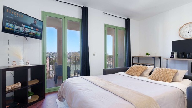 Une chambre avec un lit, une télévision, un balcon et un coin repas.