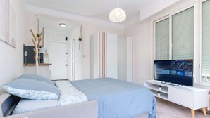 Ein modernes Schlafzimmer mit Bett, Fernseher und Kleiderschrank.