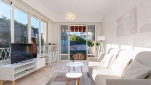 Ein modernes Wohnzimmer mit Flachbildfernseher, einer Couch, einem Couchtisch und einem Balkon mit Blick.