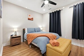 A bedroom with a bed, bedside table, lamp, and a small stool. - Modern Durham retreat / 10 mins from Duke and downtown Durham (Durham)