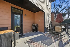 An outdoor patio with a wooden table and chairs, a grill, and a covered seating area. - Modern Durham retreat / 10 mins from Duke and downtown Durham (Durham)