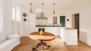Una cucina moderna con mobili bianchi, un tavolo da pranzo in legno e lampade a sospensione.