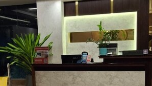 A reception desk with a marble top, a potted plant, and a sign on the left. - Hotel Amulya Royal Inn  (Bengaluru)