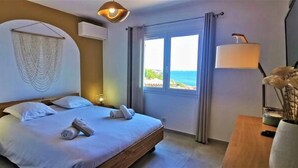 A bedroom with a bed, a bedside table with a lamp, a window with curtains, and a view of the sea. - Villa Premium à Saint-Raphaël - Heated pool, 6 suites and sea view (Saint-Raphaël)