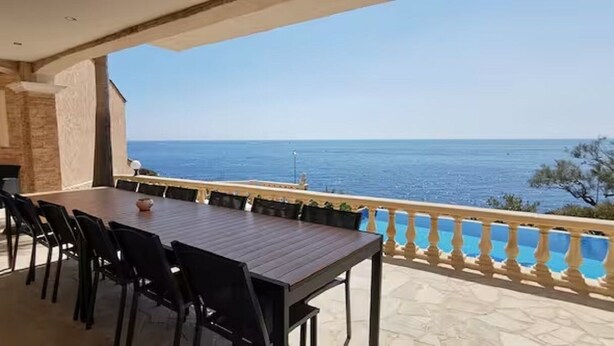 A terrace with a view of the sea, a table with chairs, and a stone wall. - Villa Premium à Saint-Raphaël - Heated pool, 6 suites and sea view (Saint-Raphaël)