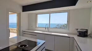 A modern kitchen with a view of the sea, a built-in stove, and a toaster on the counter. - Villa Premium à Saint-Raphaël - Heated pool, 6 suites and sea view (Saint-Raphaël)