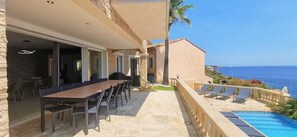 Uma villa com área de refeições, espaço para sentar ao ar livre e piscina com vista para o mar.