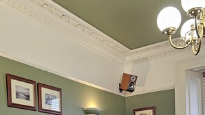 Una habitación con un sofá de cuero negro, una mesa de centro de madera y cuadros en la pared.
