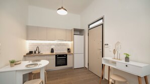 Une cuisine compacte avec un coin repas, un four encastré et un plan de travail blanc.