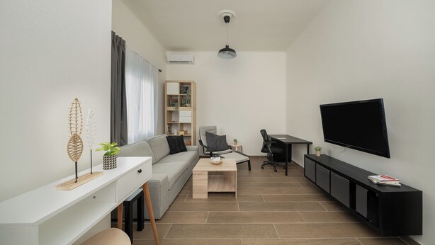 Un salon moderne comprenant un canapé, une table basse, un téléviseur et un bureau avec une chaise.