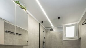 Une salle de bain moderne avec un lavabo blanc, un miroir et une douche.