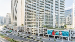 Un immeuble moderne de grande hauteur, doté de nombreux balcons et d’un grand panneau publicitaire.
