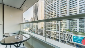 Un balcon doté d’une balustrade en verre, une petite table ronde et deux chaises.