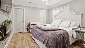 Una camera da letto con un letto, una ventola a soffitto, una finestra con persiane e una porta.