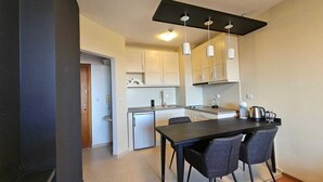 Eine kompakte Küche mit Essbereich, ausgestattet mit einer dunklen Arbeitsplatte, modernen Pendelleuchten und einer kleinen Kücheninsel.