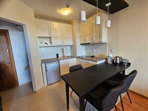 A compact kitchen with a dining table, chairs, and a refrigerator. - Elegant apartment near the ski slopes in Bansko (Bansko)