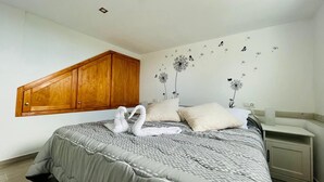 A bedroom with a large bed, wooden headboard, and wall decals of swans and dandelions. - La Casita de La Pared: Ideal house for families, with game room. (LOS REALEJOS)