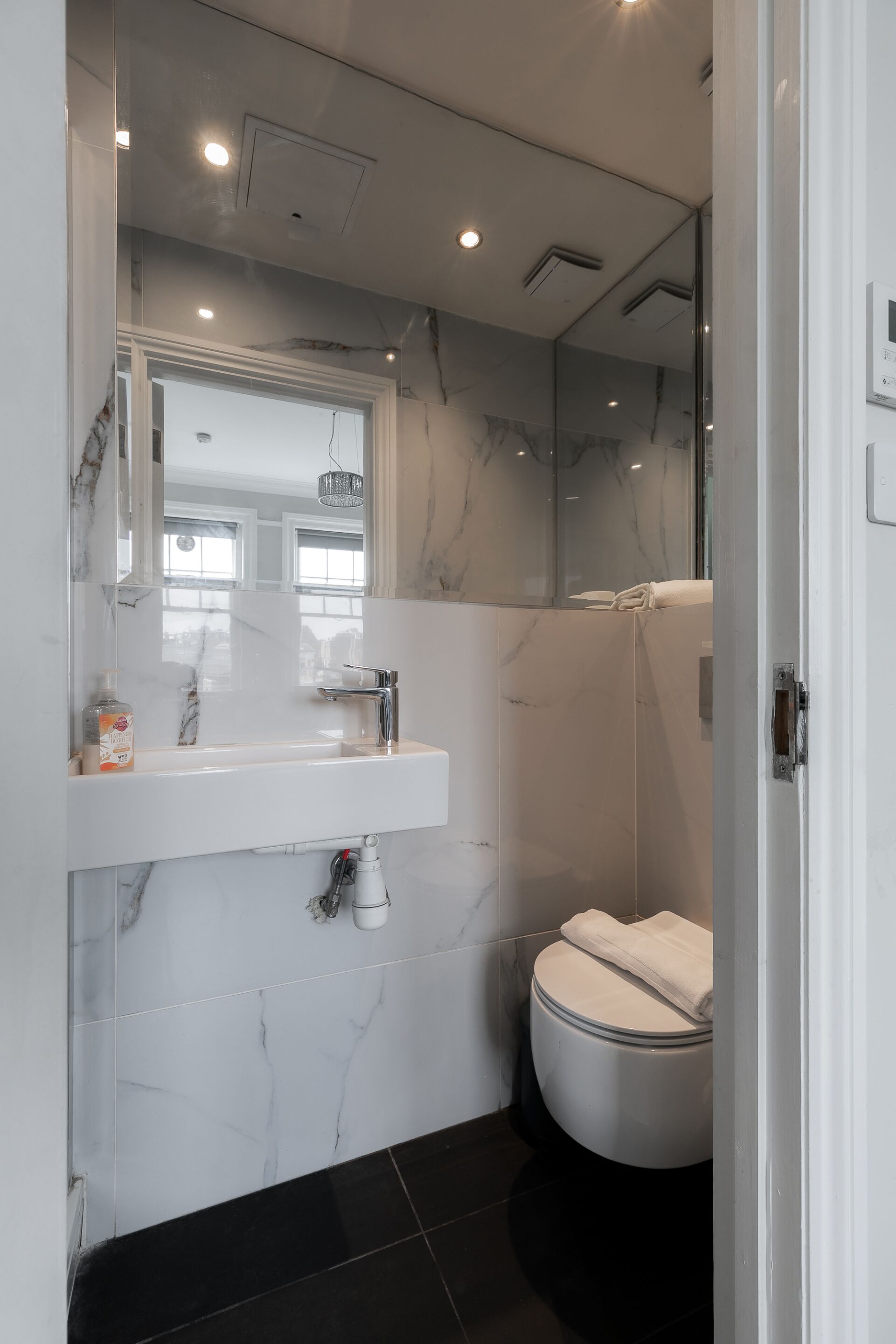 Een moderne badkamer met een marmeren wastafel, een toilet en een douchecabine met glazen wanden.