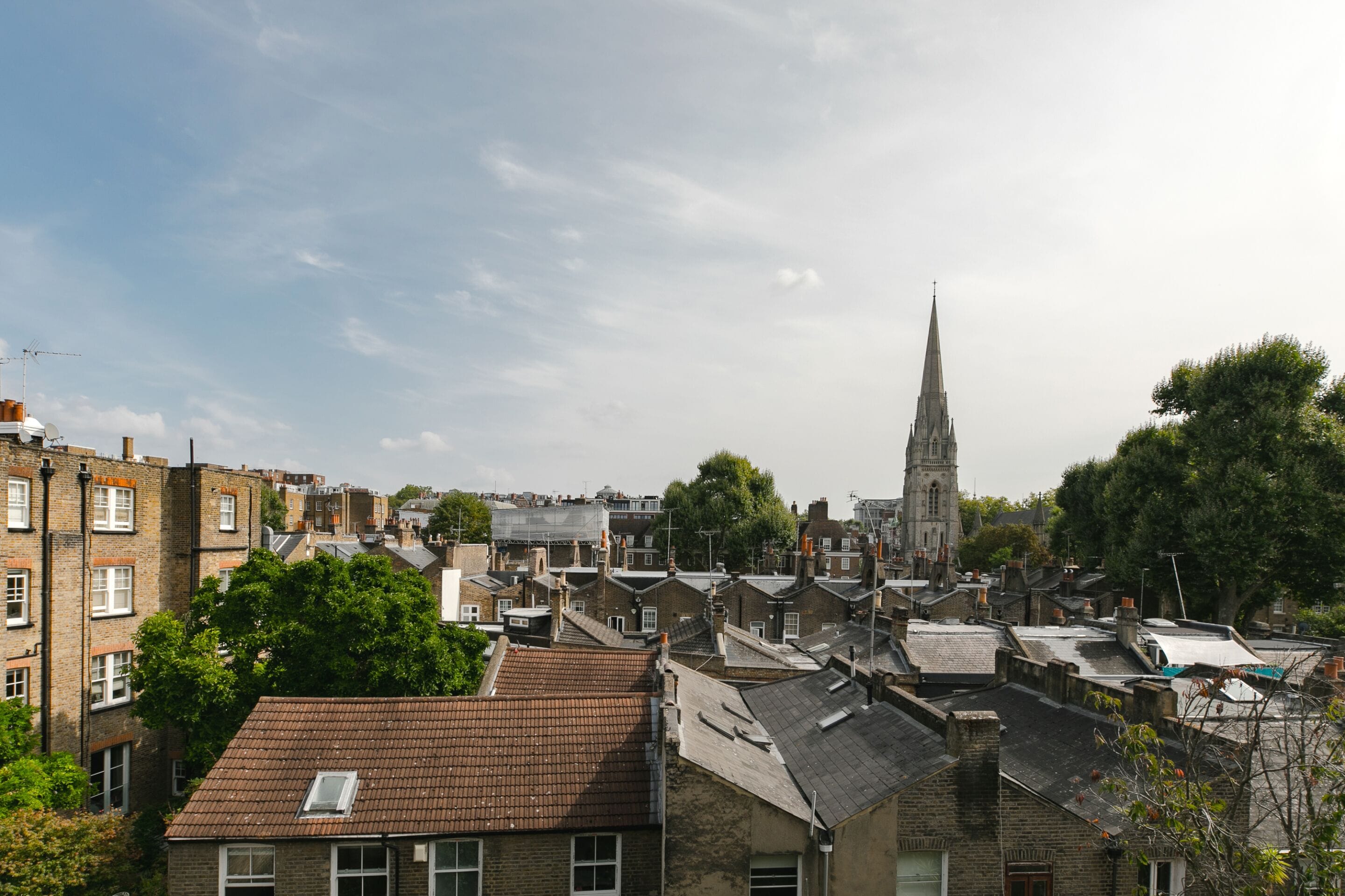 A view of a town with a prominent church spire, residential buildings, and a mix of older and newer architecture.