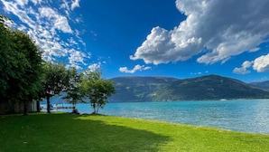 Zona verde con un lago y montañas al fondo.