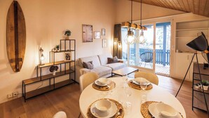 A dining area with a round table set for two, a sofa, and a balcony with a view. - Surfers Lodge | Lake View & Pool (Därligen)