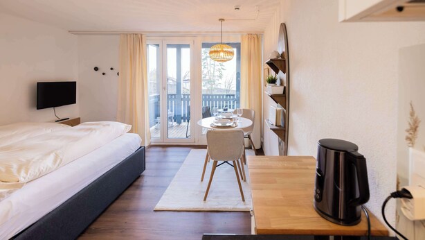A hotel room with a bed, a desk, a chair, a coffee maker, and a TV. - Surfers Studio | Lake View & Pool (Därligen)