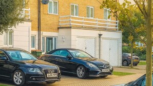 A residential building with a brick facade, multiple windows, and a gated garage. - Room-luxury Homestay Near Excel London C (London)