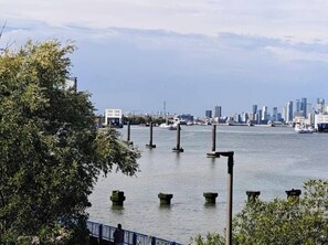 A waterfront view with a city skyline in the background, a bridge with pillars, and a body of water. - Room-luxury Guest Room in East London wi (London)