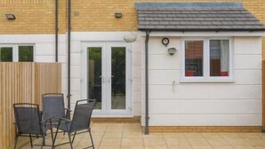 A two-story residential building with a tiled patio, a small white annex, and a wooden fence. - Room-luxury Room in East London Excel (London)