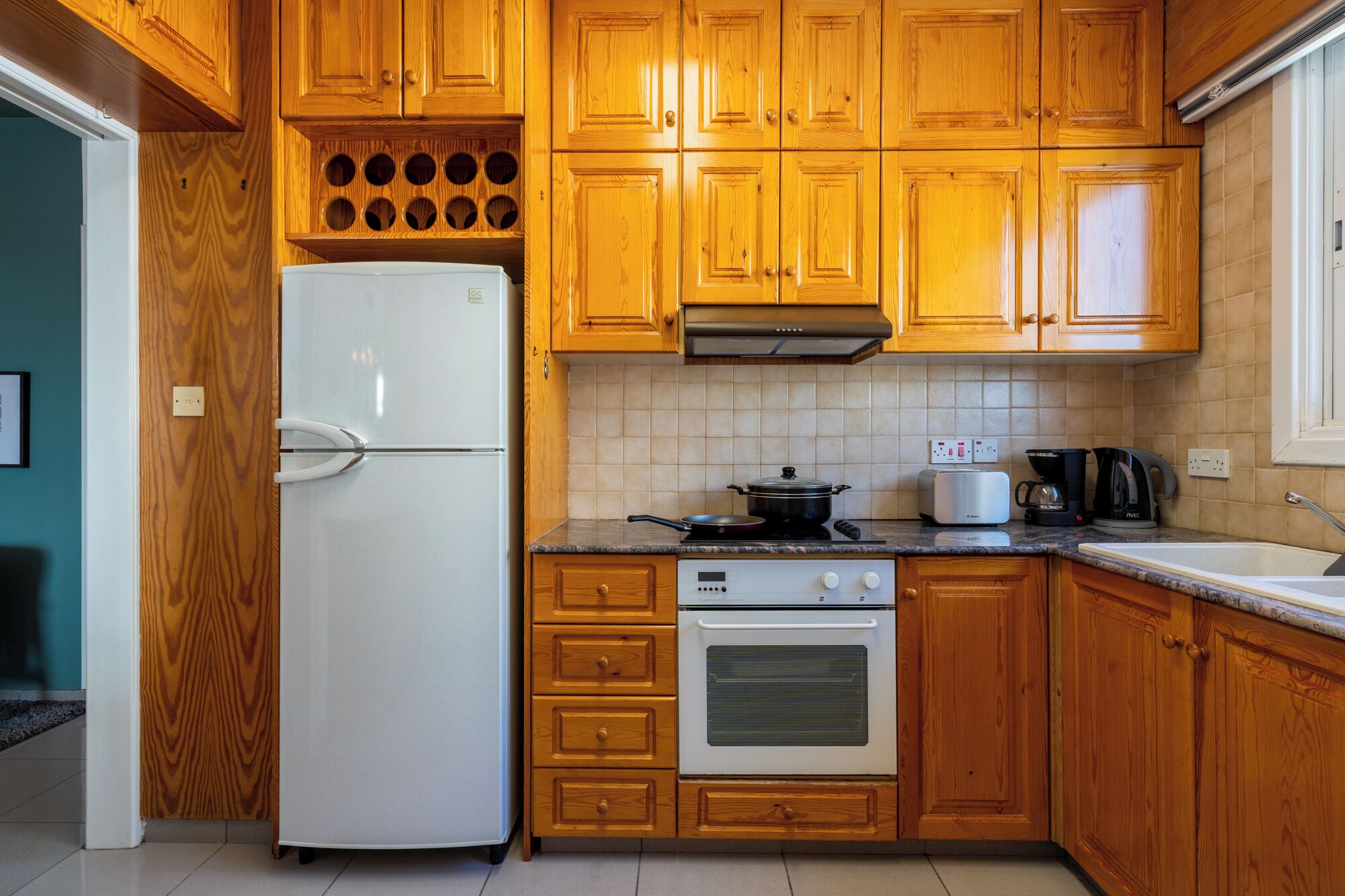 Une cuisine avec des meubles de rangement en bois, un réfrigérateur blanc, une cuisinière et un four à micro-ondes.