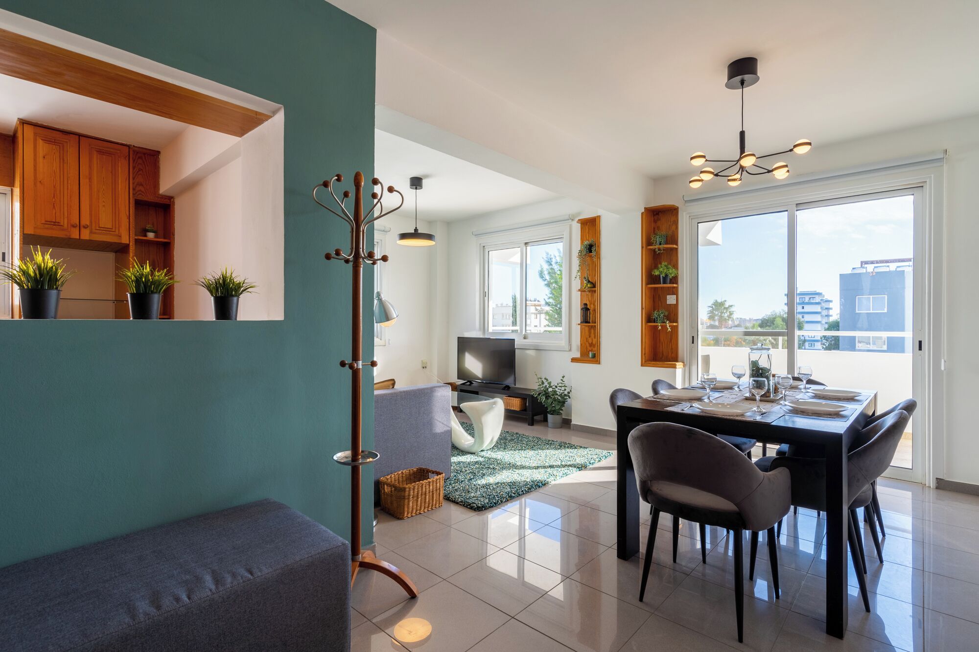 A modern living space with a dining area, a TV, and a balcony with plants.
