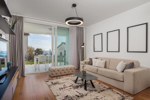 A modern living room with a sofa, a coffee table, and a view of a balcony. - Apartment Lara - rooftop pool, 2 bedroom, sea view (Ičići)