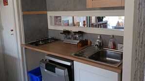 Eine kompakte Küche mit Holzarbeitsplatte, integriertem Spülbecken und Geschirrspüler.